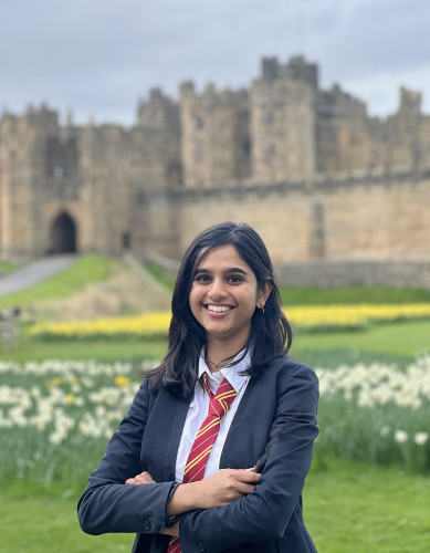 Shruthi Magesh smiles and poses for a portrait photo outside a medieval castle