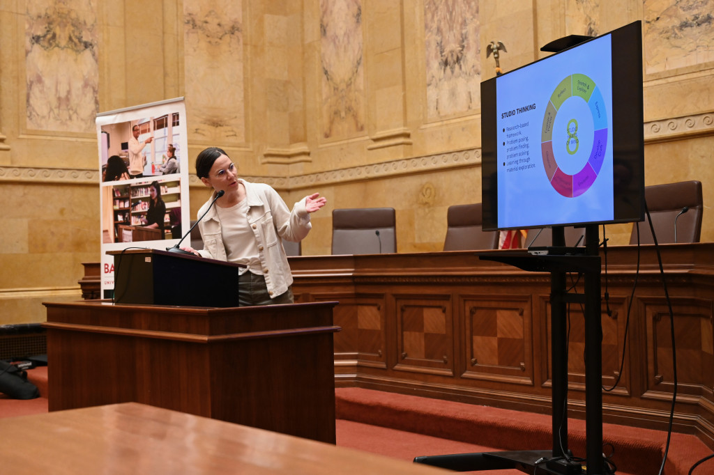 Hoefferle stands behind a heavy wooden podium in a marble-walled room of the State Capitol Building. She directs herself and points to a nearby TV screen that displays her research.