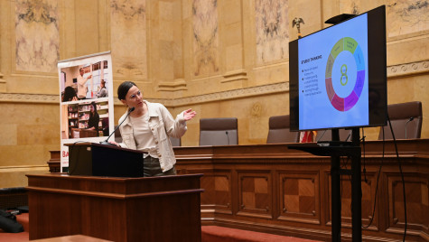 Hoefferle stands behind a heavy wooden podium in a marble-walled room of the State Capitol Building. She directs herself and points to a nearby TV screen that displays her research.