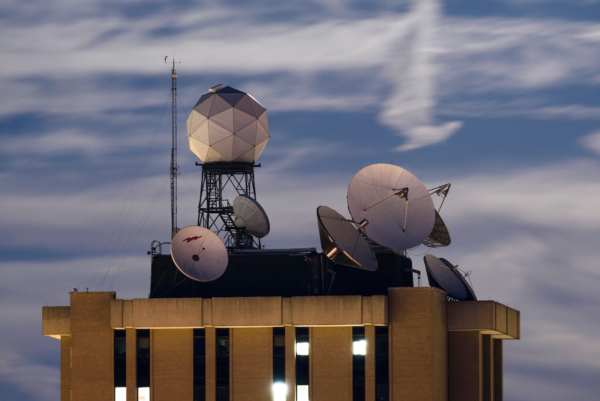 Modern weather sensing equipment, including antennae and satellites, sit atop a research building on the UW–Madison campus.