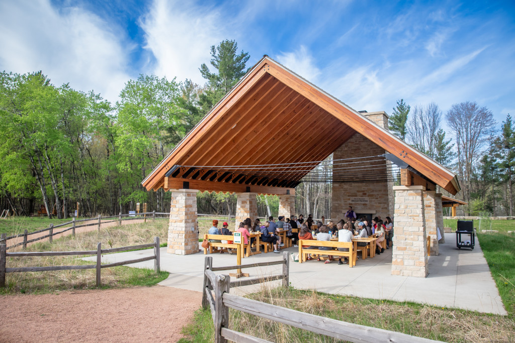A group of people gather at an outdoor pavilion.