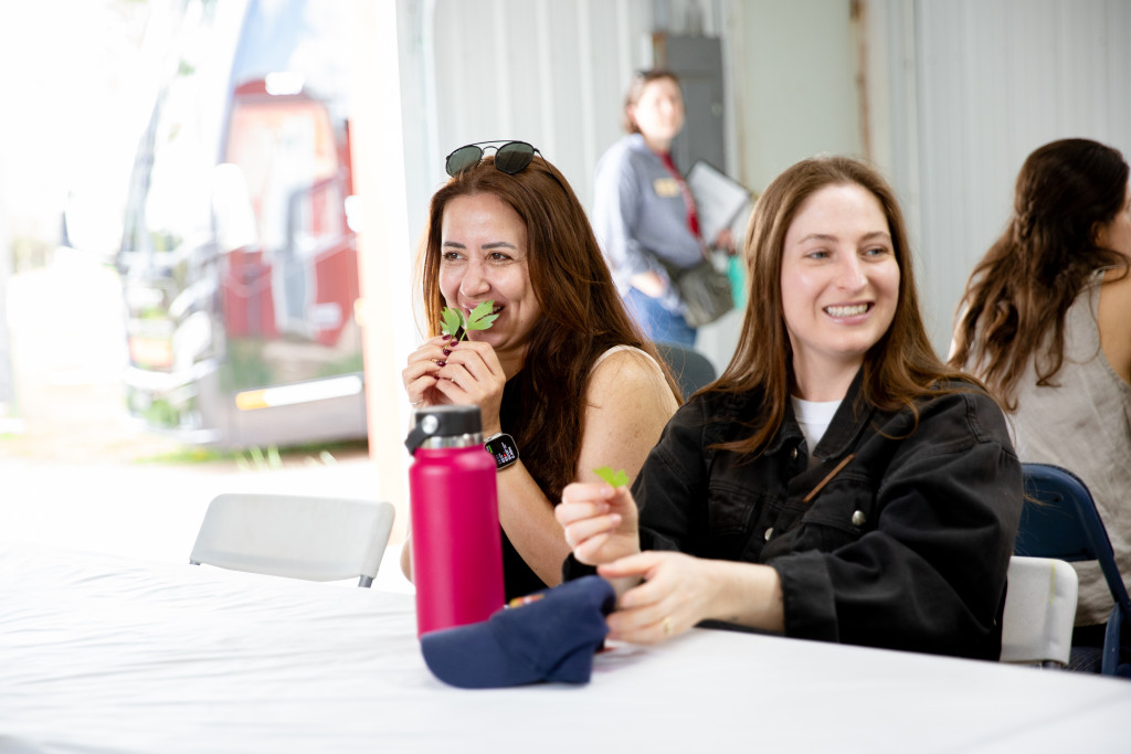 Two women sample a green vegetable.