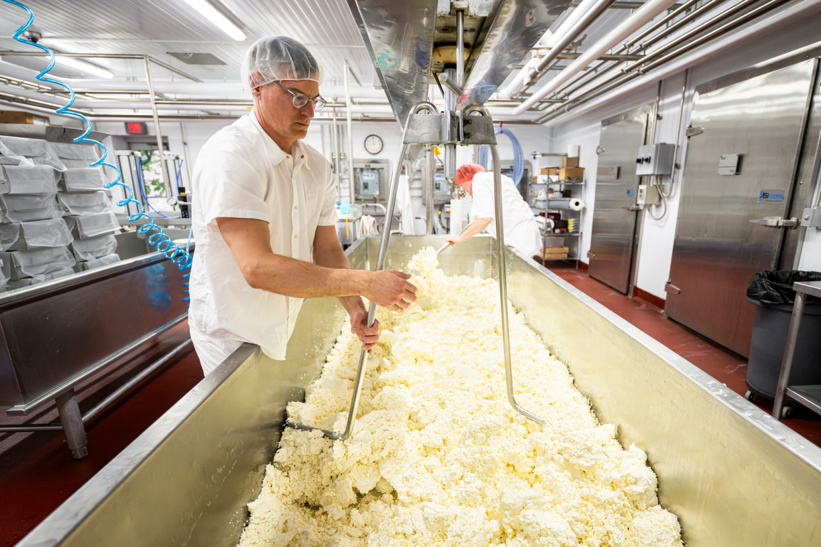 Niemiec stands next to a large metal cheese vat here he manually controls the equipment that separates the cheese curds from the whey.