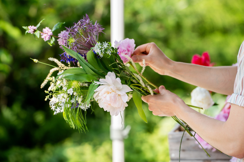 A pair of hands are shown choosing some flowers out of a bunch.
