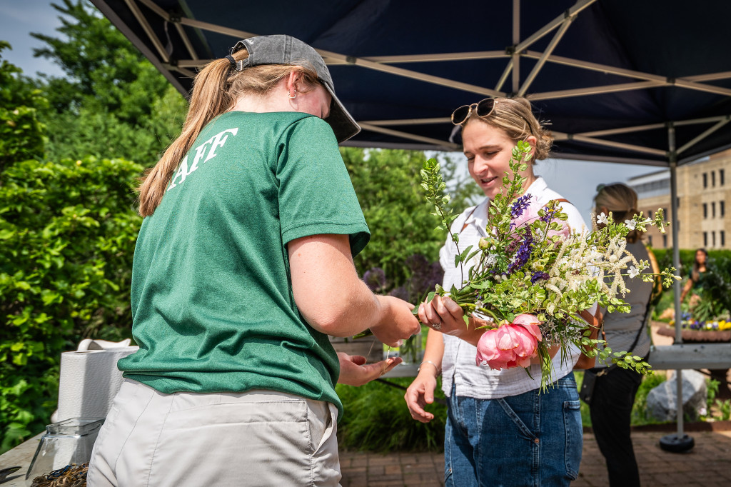 A person proudly holds a flower bouquet as another looks at it.