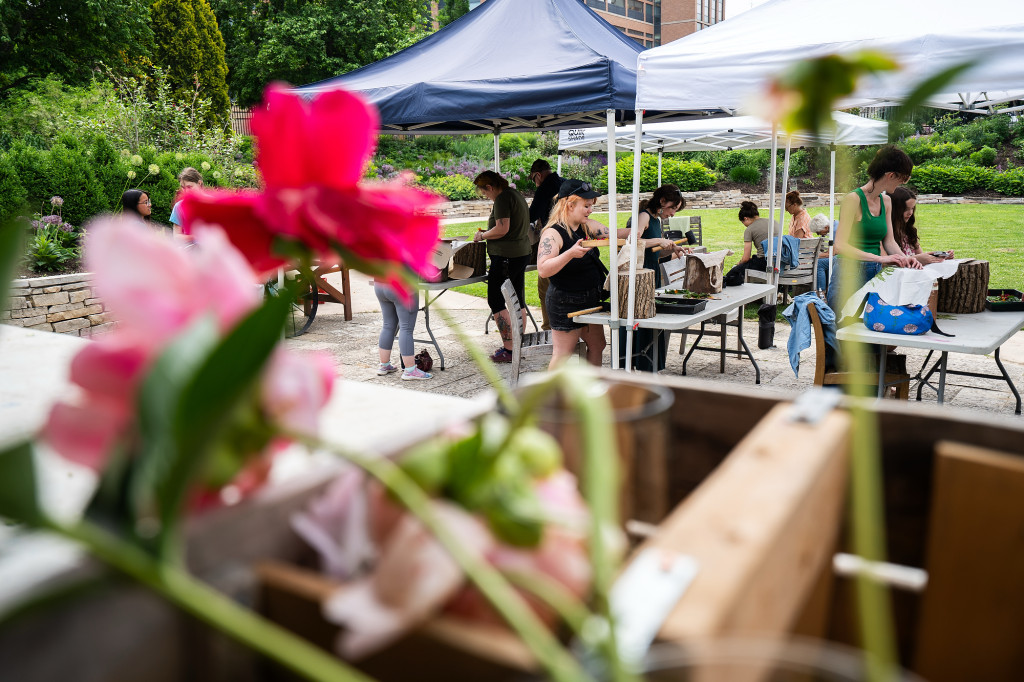 People actively pound flowers with hammers on a table.