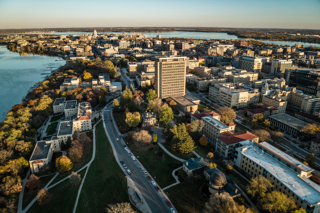The UW campus and Madison skyline and Lake Mendota and Lake Monona are photographed looking east above Waters Residence Hall by a drone at sunset in the fall (autumn) at the University of Wisconsin–Madison.