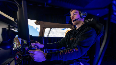A student sits in the cockpit of a aviation aircraft simulator.