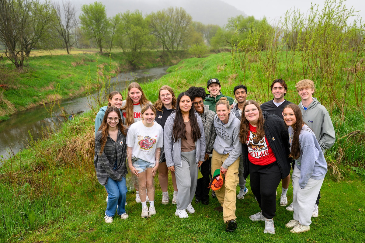 A group of UW students pose with their professor for a class photo along the bank of Coon Creek.