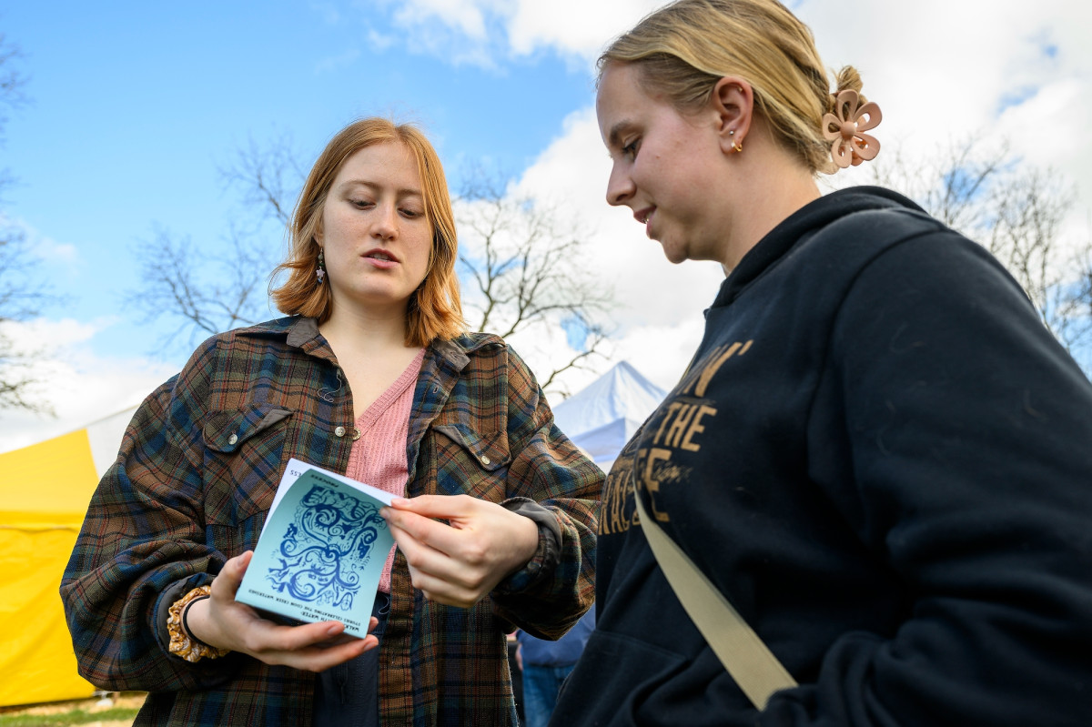 Hamilton shows a small pamphlet to one of the Conservation Day attendees.