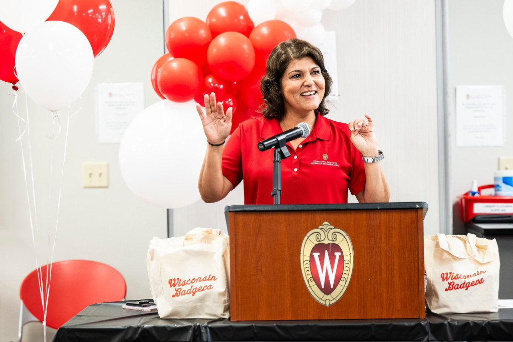 Gonzalez stands behind a podium and speaks to the crowd and the partnership space.
