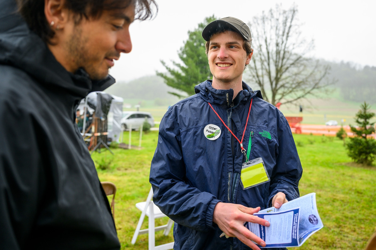 Sellers speaks to a community member while holding a pamphlet.