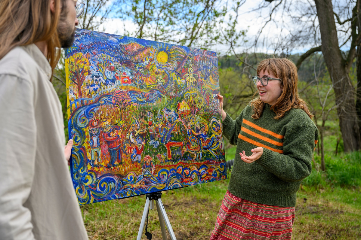 Whisler gestures as she explains her painting to an onlooker.