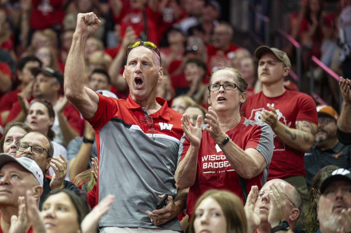 Two fans stand among a sea of Badger fans and cheer on the team.