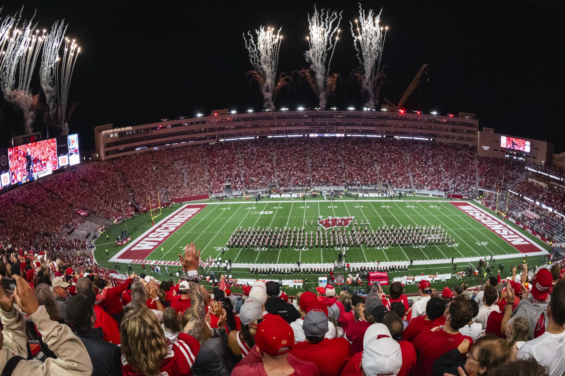 An overview of the Camp Randall stadium bowl, with the Marching Band on the field and fireworks in the sky.
