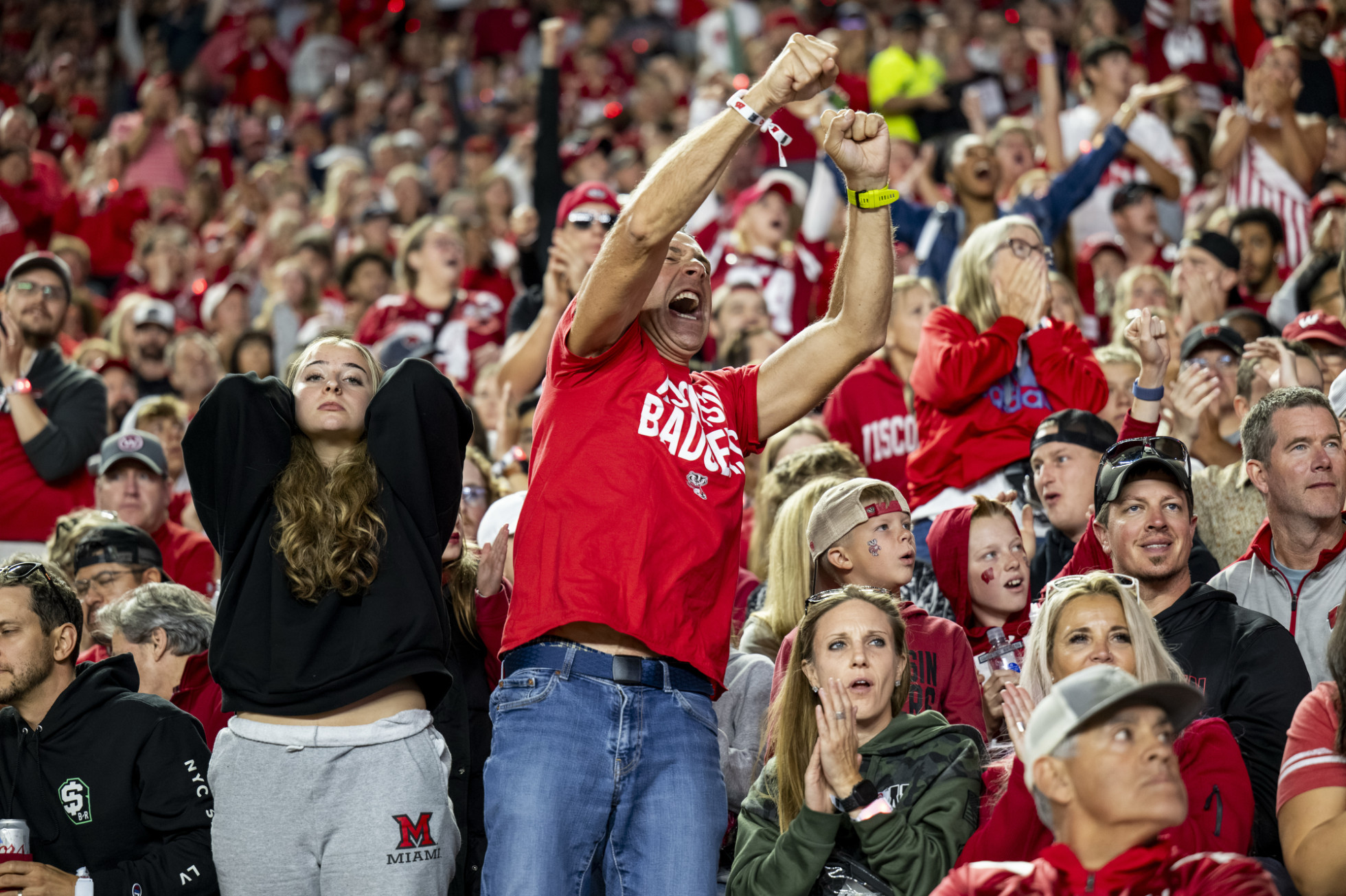 A Miami RedHawk fan puts her head over her head in despair, as a Badger fan celebrates next to her in the crowd. 