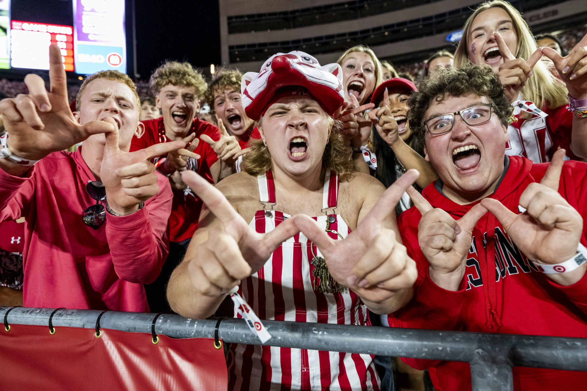 UW fans in the student section make Ws with their hands while celebrating.