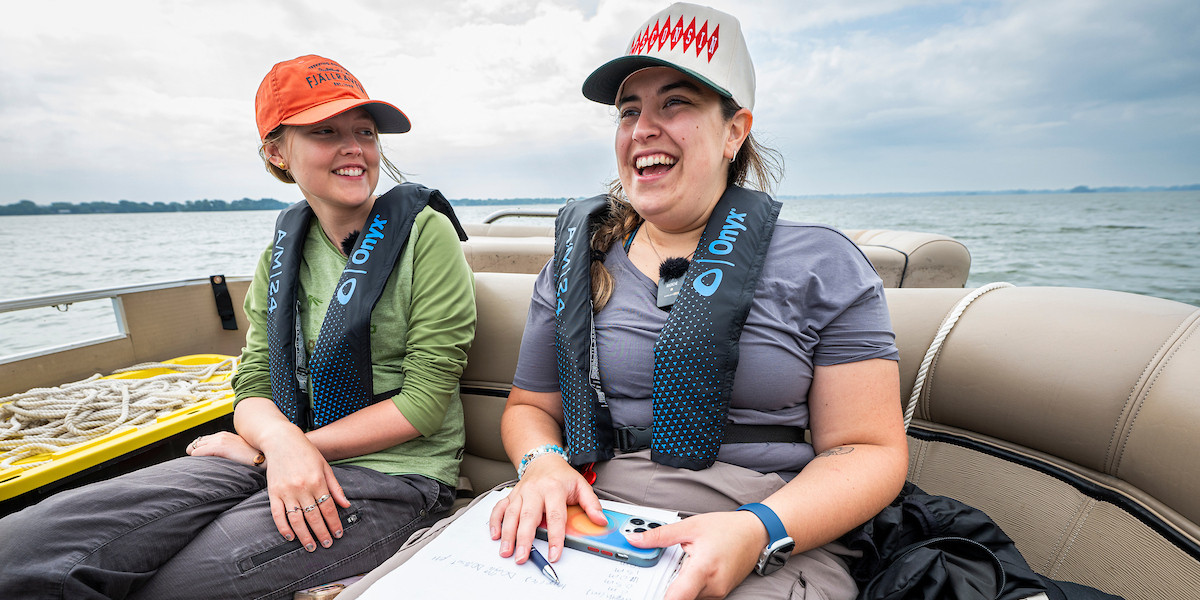 Two people sitting on a boat, look at some papers and smile.