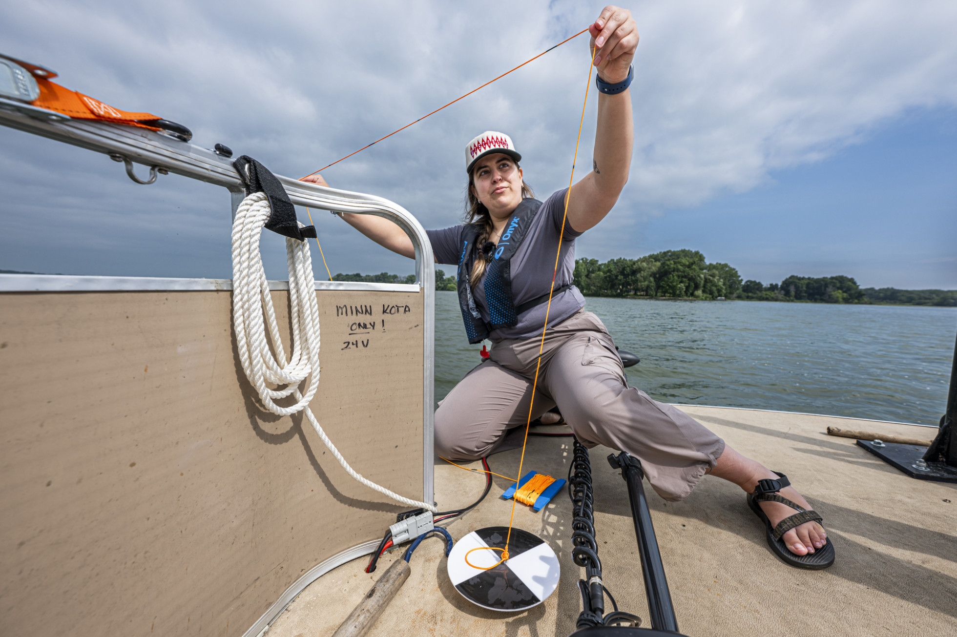 Bollini crouches on a boat and holds a string above her head.