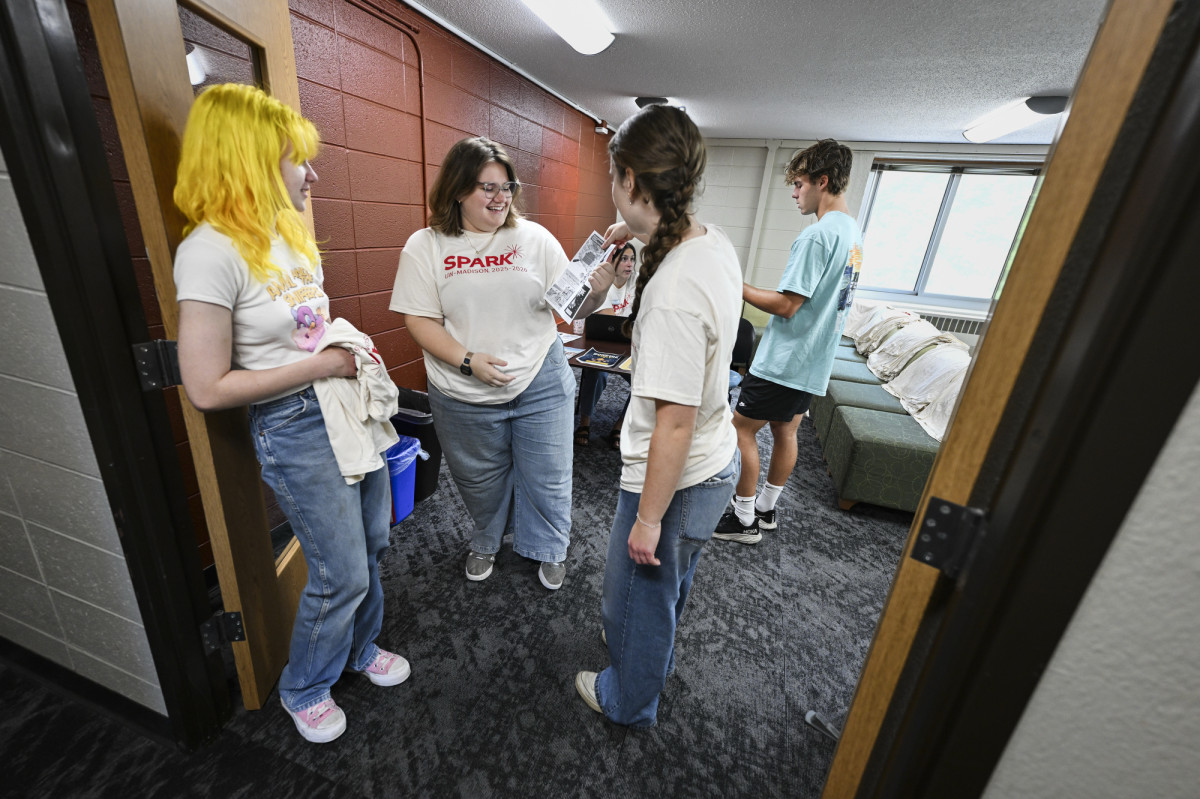 Wearing white Spark shirts, peer mentors Gabby Heling and Rowan O’laughlin talk to a new resident in Bradley Residence Hall.