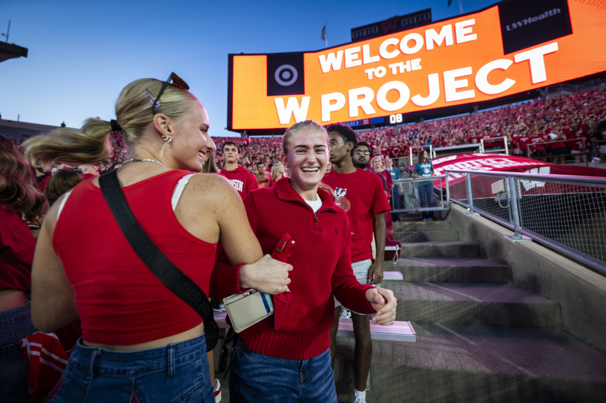 Students dance in a stadium's stands.