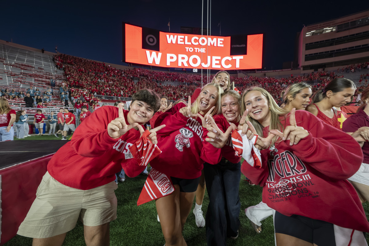 Students make the W sign and cheer as they smile at the camera.