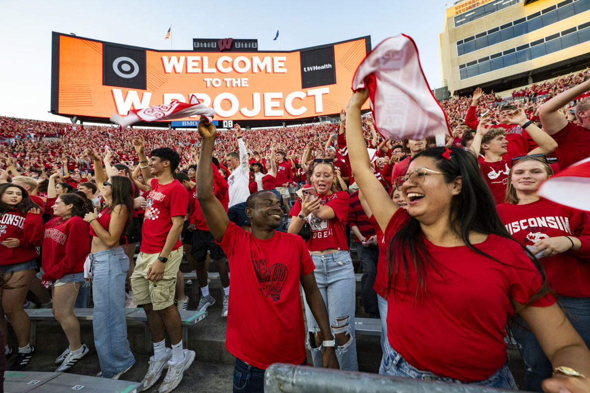 People cheer in a football stadium stands.