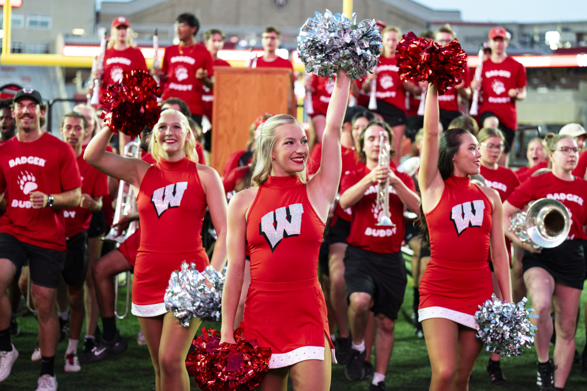 Cheerleaders in red dresses with a W on them cheer.
