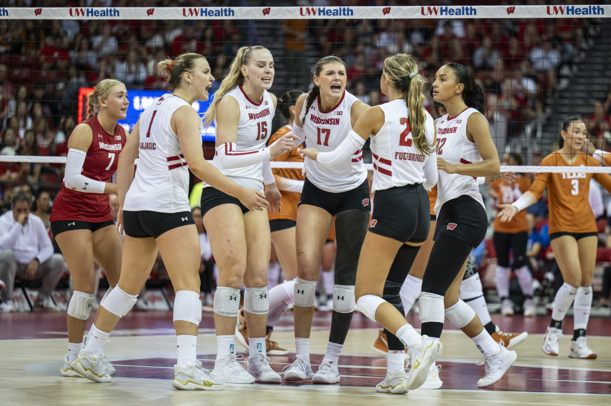 The Badger women's volleyball team gathers in mid-court to cheer each other on after winning a point.