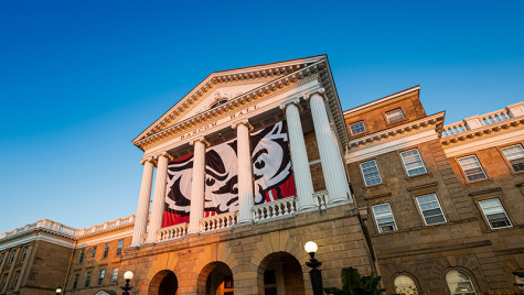 A front-facing photo of Bascom Hall, with a Bucky Badger logo on the banner.