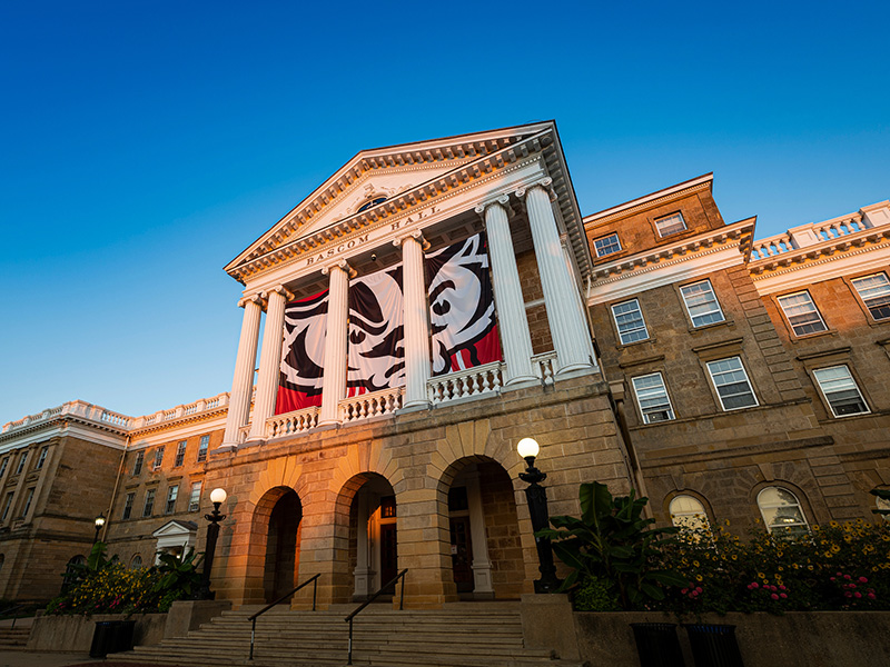 A front-facing photo of Bascom Hall, with a Bucky Badger logo on the banner.