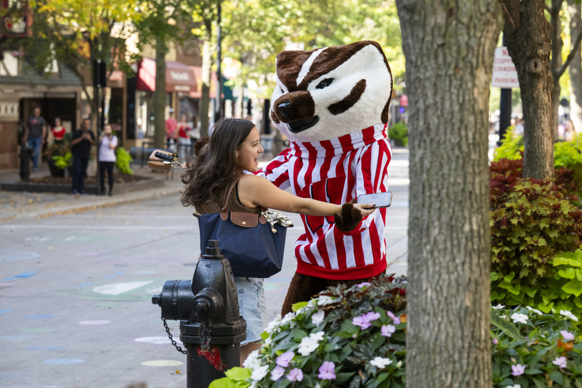 Bucky Badger dances hand in hand with a passerby on State Street. 