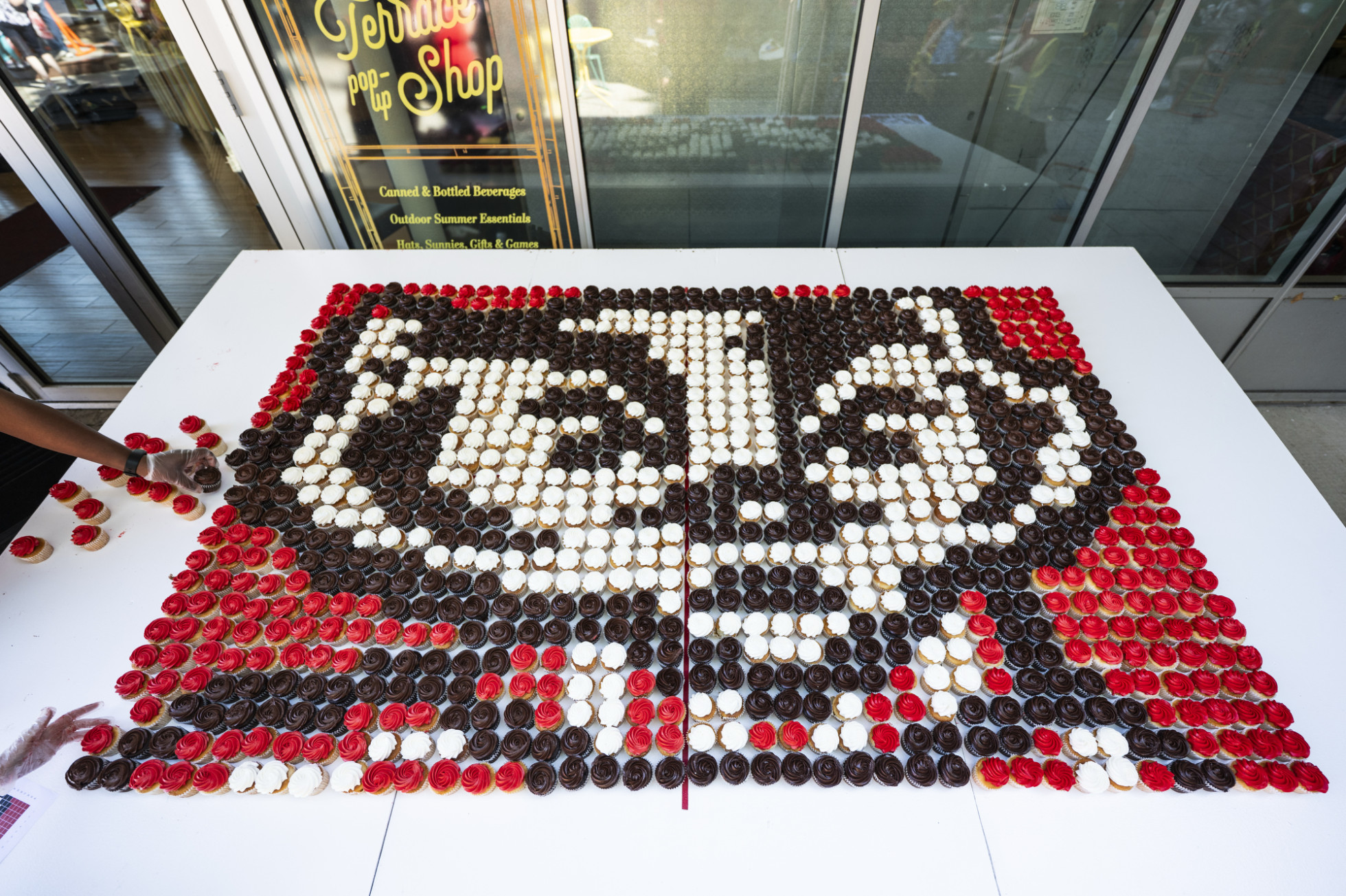 Dozens of red, black and white frosted cupcakes  are arranged in the image of Bucky Badger's face logo. 