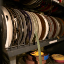 A shelf filled with colorful archival film reels, some with hanging strips.