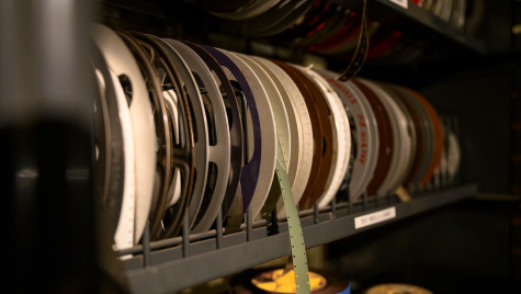 A shelf filled with colorful archival film reels, some with hanging strips.