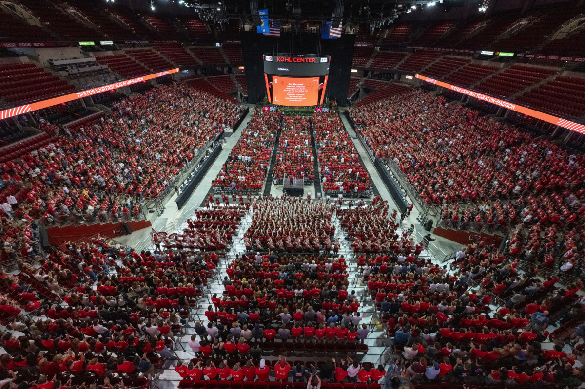 Students, many wearing Badger red shirts, fill the lower level of the Kohl Center. 