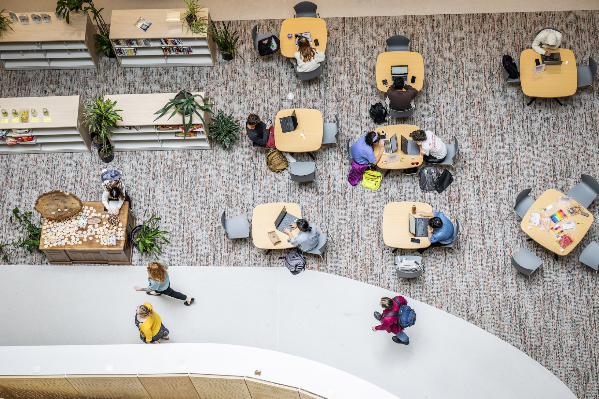 Photographed from above, people sit at small two- and three-person tables studying.