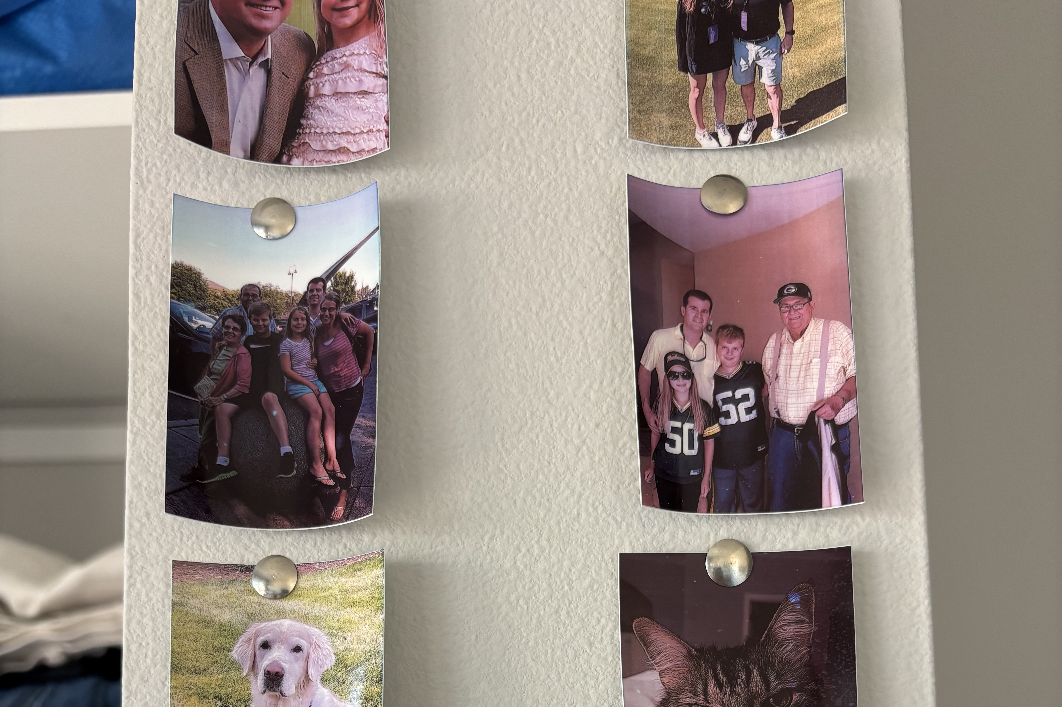 Two rows of personal photos hang on a wall.