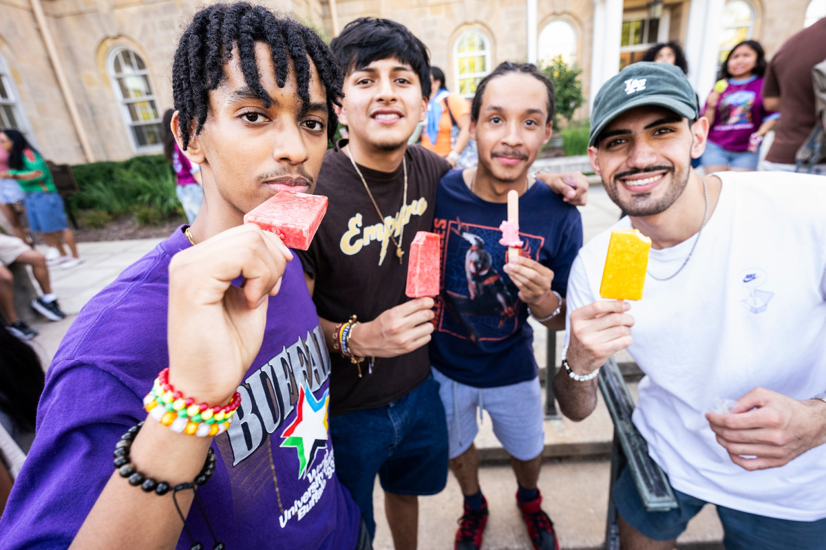 Four students group together for a photo while eating frozen fruit juice deserts called paletas.