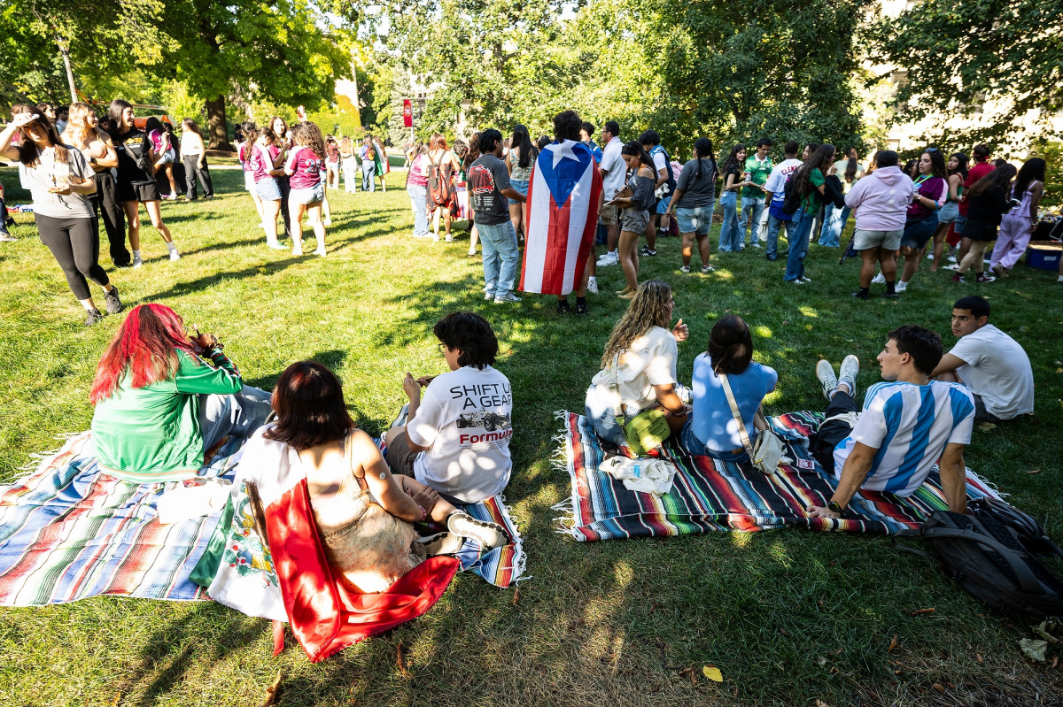Groups of students stand or sit on picnic blankets on Bascom Hill.
