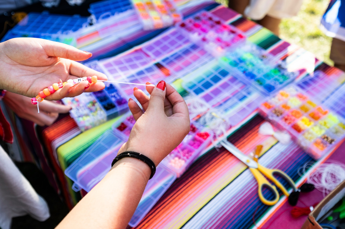 A close-up photo of hands making a beaded friendship bracelet.