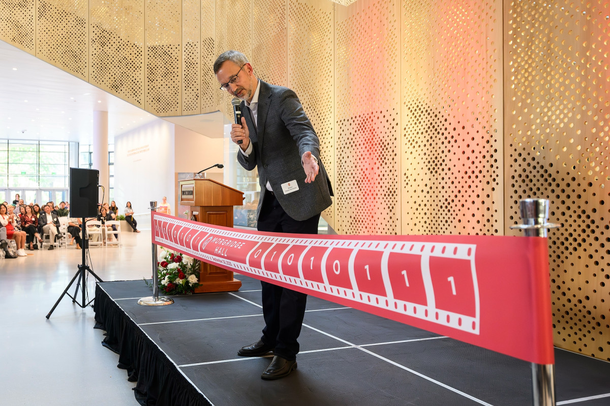 Arpaci-Dussea stands behind and points to a red ribbon that spans the length of the stage.