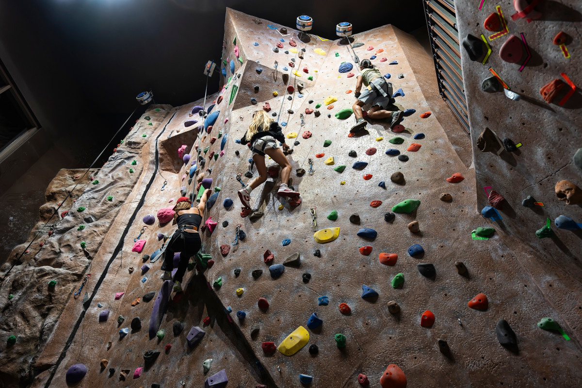 A view of a climbing wall with students scaling one section. 