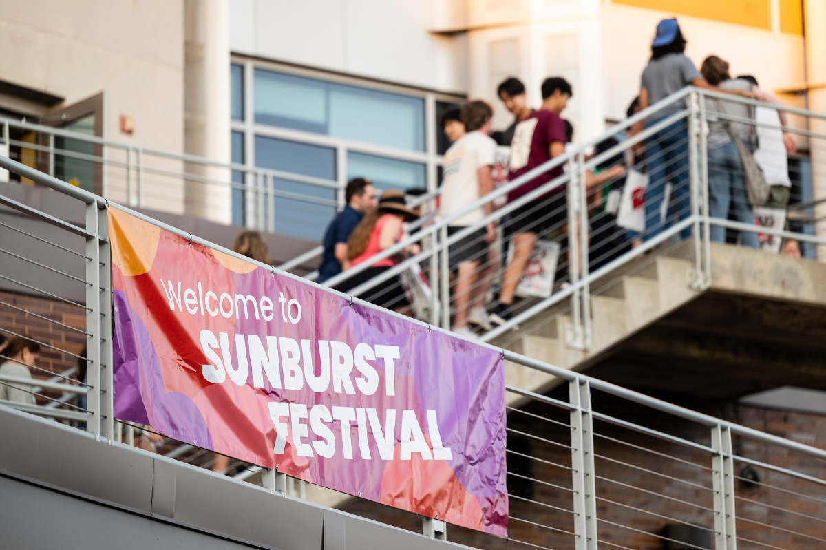 Students walk up the exterior stairs of Union South, which holds a banner that reads, 'Welcome to Sunburst Festival.' 