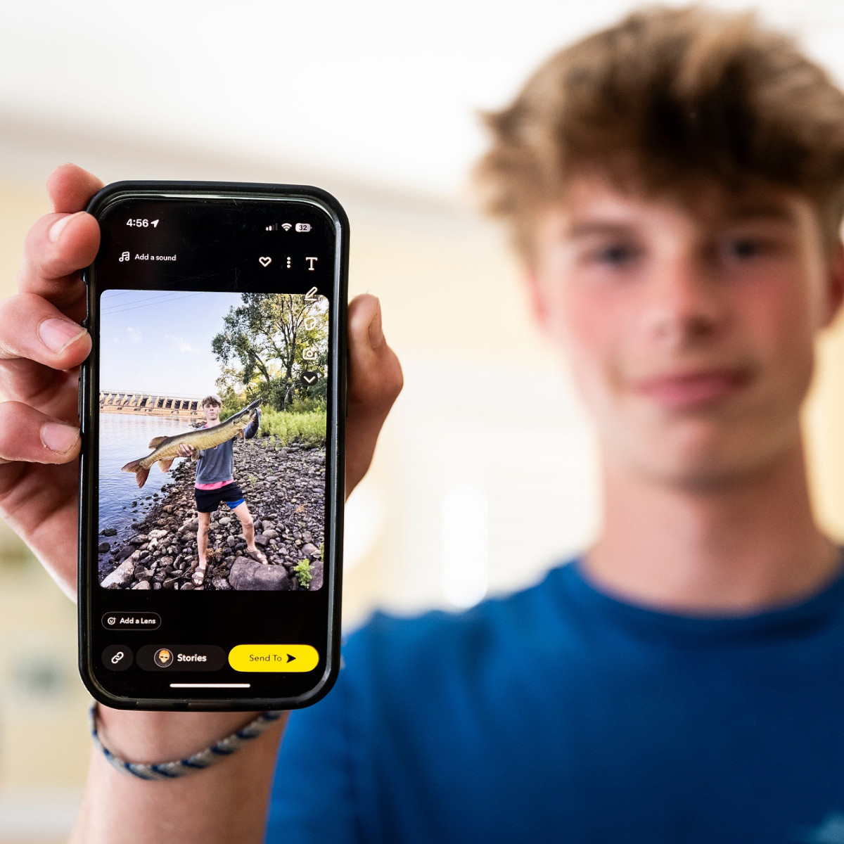 Weisensel holds up his phone to the camera, which shows a picture of him holding a large muskie that he caught in the Wisconsin River.
