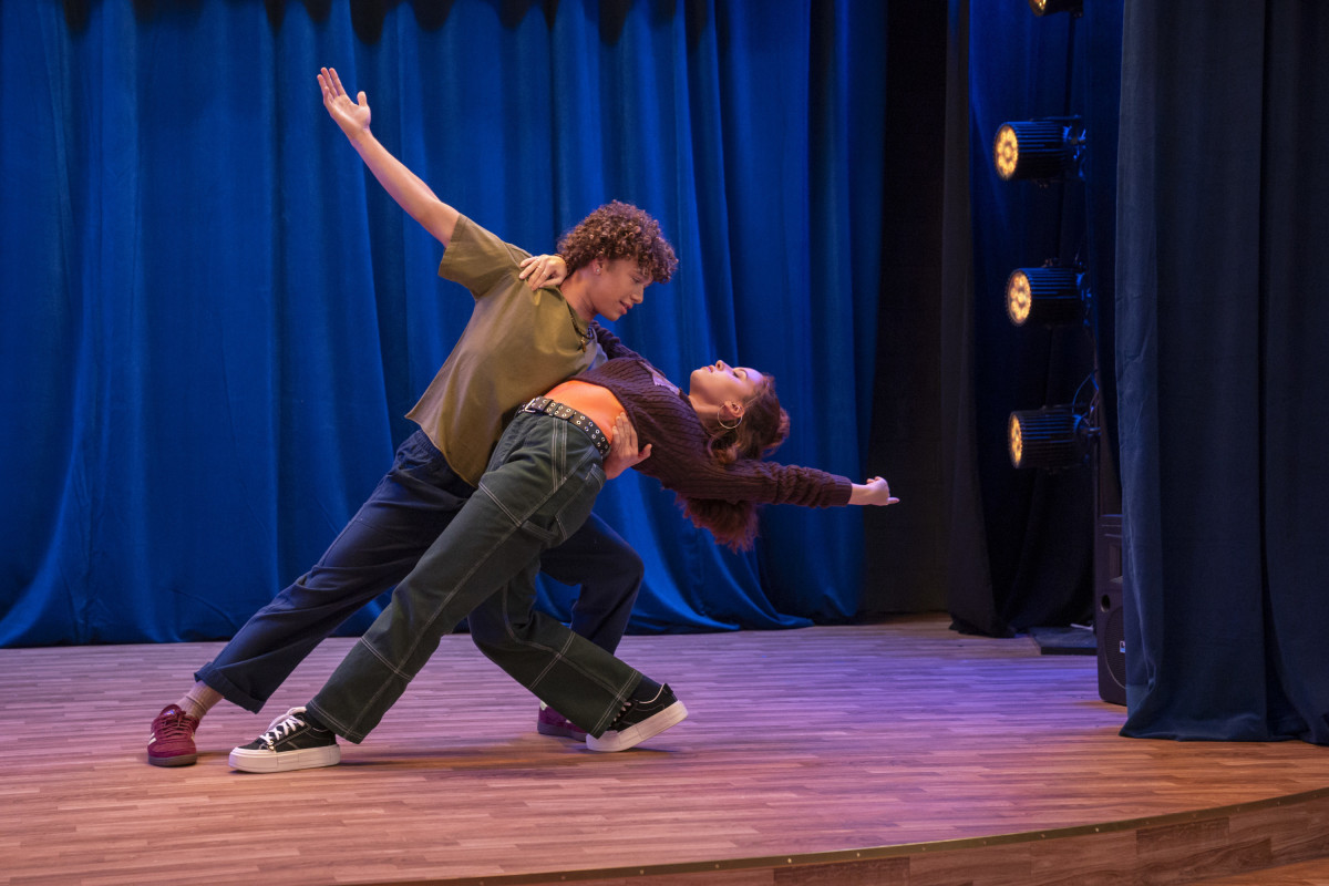Actor Nate Buescher performs a dance with costar Lumi Pollack on a stage.