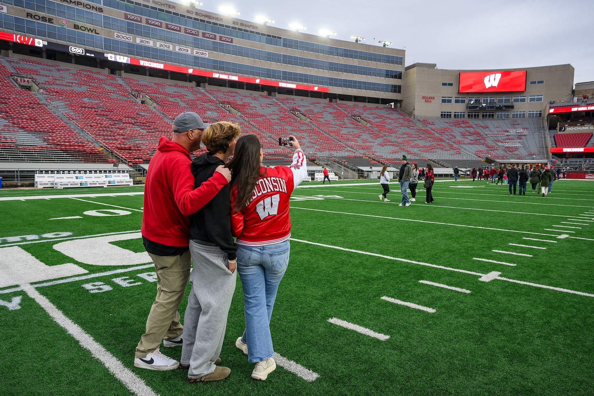 Three people stands on the football field and take a selfie of themselves.