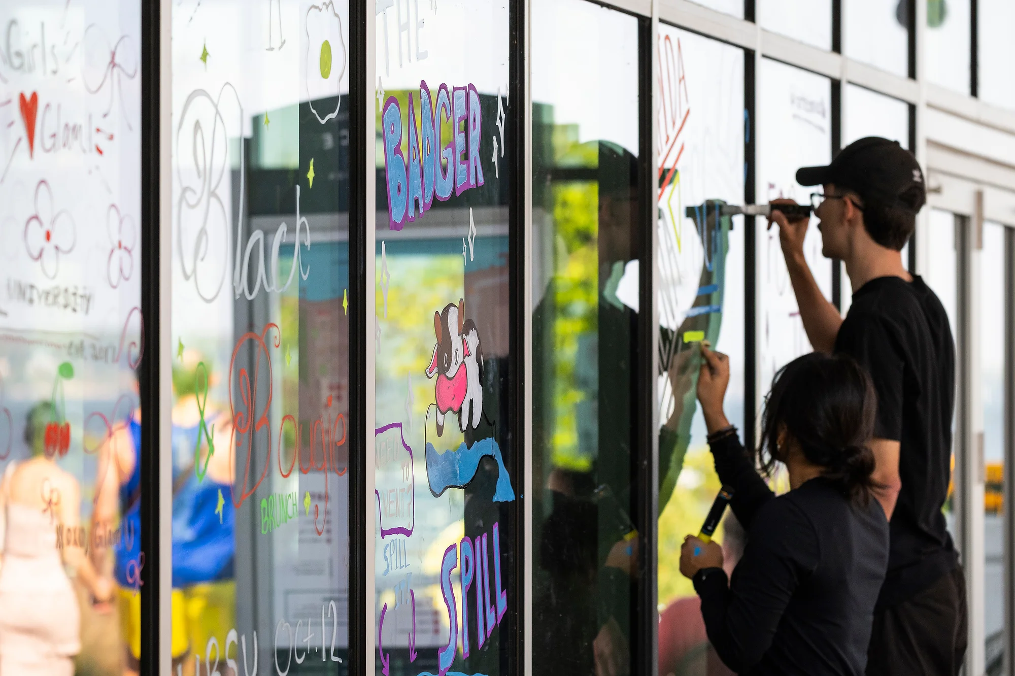 Two students write messages on a window