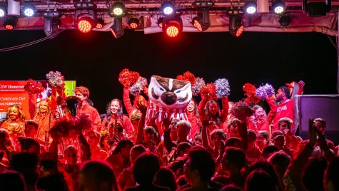 A crowd in red light cheers as Bucky Badger and UW-Madison’s spirit squad take the outdoor stage at the Memorial Union Terrace.