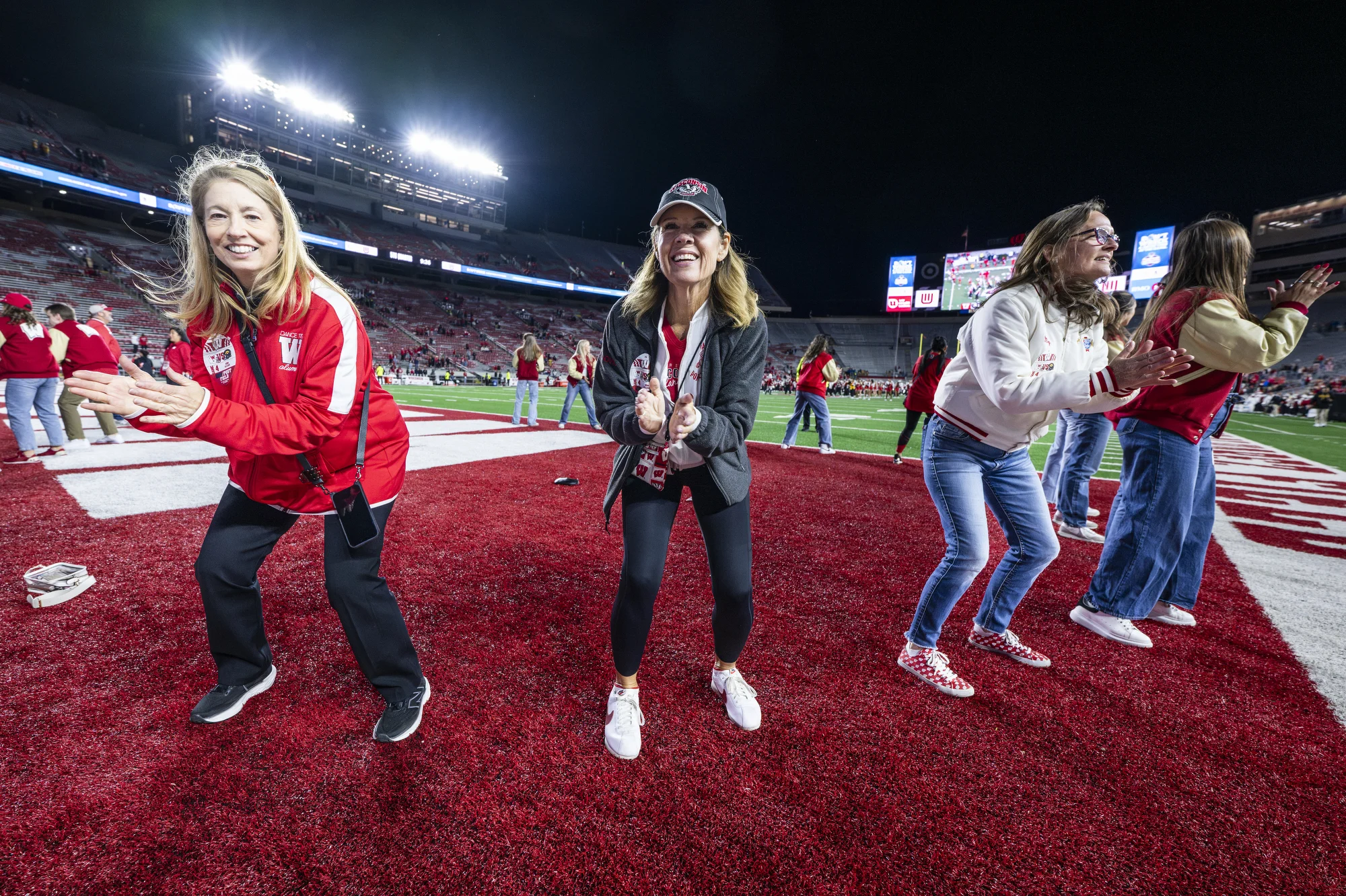 Former members of the UW Spirit Squad dance in the end zone on Camp Randall field